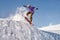 Stylish snowboarder with helmet and mask jumps from high snow slope