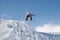 Stylish snowboarder with helmet and mask jumps from high snow slope