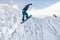 Stylish snowboarder with helmet and mask jumps from high snow slope