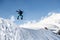 Stylish snowboarder with helmet and mask jumps from high snow slope