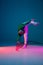 Stylish sportive boy dancing hip-hop in stylish clothes on colorful background at dance hall in neon light. Youth