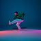 Stylish sportive boy dancing hip-hop in stylish clothes on colorful background at dance hall in neon light. Youth