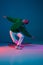 Stylish sportive boy dancing hip-hop in stylish clothes on colorful background at dance hall in neon light. Youth