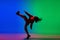 Stylish sportive girl dancing hip-hop in stylish clothes on colorful background at dance hall in neon light. Youth