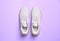Stylish sporty sneakers on light violet background, top view