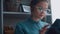 Stylish student girl sits by the window and reads an e-book