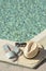 Stylish sunglasses, slippers and straw hat at poolside on sunny day, space for text. Beach accessories