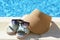 Stylish sunglasses, visor cap and slippers at poolside on sunny day. Beach accessories