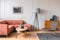 Stylish tall grey lamp in elegant living room interior with comfortable brown corner sofa