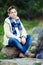 Stylish teenage boy sit on rock, nature outdoors