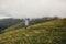 stylish traveler man in hat jumping on top of mountains with clouds. space for text. hipster guy traveling, funny emotions.