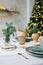 Stylish and trendy design of a festive table set for a family dinner. Vases with spruce branches, glasses and plates on the