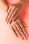 Stylish trendy french manicure. Hands of a beautiful young woman are covered by highlight on a pink background