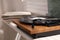 Stylish turntable with vinyl disc on windowsill in room, closeup