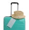 Stylish turquoise suitcase, hat and protective mask on background. Travelling during coronavirus pandemic