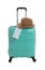 Stylish turquoise suitcase, hat and protective mask on background. Travelling during coronavirus pandemic