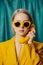 Stylish ukrainian woman in yellow sunglasses and jacket with deal phone