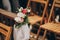 Stylish wedding decor of wooden benches in church for holy matrimony. Beautiful roses and tulle bouquets on wooden chairs,