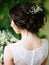 Stylish wedding hairdo. Bridal portrait in white lace wedding dress and oversized bouquet, rear view.