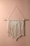 Stylish white macrame hanging on pink wall