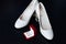 Stylish white shoes of the bride and wedding engagement gold rings in a red decorative box