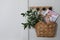 Stylish wicker basket with bouquet of flowers and magazine hanging on wooden rack indoors, space for text