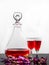 A stylish wine decanter with red wine, two wineglasses & petals