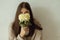 Stylish woman in cozy knitted sweater posing with chrysanthemum on background of rural authentic wall. Moody fall. Portrait of