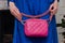 stylish woman of fashionable woman has a small quilted pink leather bag (clutch) on the background of a bright blue (electric) dr