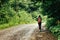 Stylish woman hipster traveler walking on the road with backpack