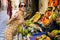 Stylish woman leaning toward stall with assorted fruits on street