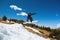 Stylish woman snowboarder makes a trick in flight. Snowboard jump from a kicker against the backdrop of mountains