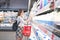 Stylish woman is standing in the milk department of a supermarket with milk in her hands and looking at the label