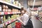 Stylish woman stands at the supermarket near the canned vegetable counter and looks at the cans in her hands