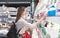 Stylish woman takes a yogurt from the shelf of the dairy department of the supermarket