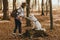 Stylish woman training white dog to give paw in sunny autumn woods. Cute swiss shepherd puppy