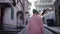 Stylish woman traveler walking through the narrow streets of the ancient city, back view