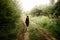 Stylish woman traveler walking in sun light in woods with photo