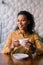 Stylish woman wearing accessories and yellow blouse drinking coffee