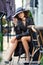 Stylish woman wearing old fashioned coat, sitting behind the table in street outdoor cafe after the rain