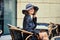 Stylish woman wearing old fashioned coat, sitting behind the table in street outdoor cafe after the rain