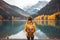 Stylish Woman in Yellow Jacket Admiring Autumn Lake and Mountain Panorama. Generative Ai