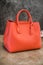 Stylish women`s handbag on a stone background. Orange, light coral. Clothing and accessories.Elegant outfit