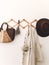 Stylish wooden hanger with straw bag, linen tote bag, brown hat and linen cloth. Countryside still life. Zero waste home concept.