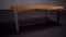 Stylish wooden table in empty room. Stock footage. Beautiful wooden table with iron legs stands in middle of empty gray