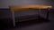 Stylish wooden table in empty room. Stock footage. Beautiful wooden table with iron legs stands in middle of empty gray