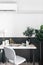 Stylish working corner in scandinavian style with nice decoration and artificial plant in natural light setting scene / interior