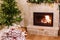 Stylish wrapped christmas gifts, christmas tree with festive lights and cozy burning fireplace. Atmospheric Christmas eve, holiday