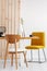 Stylish yellow chair at wooden dining table in trendy interior