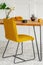 Stylish yellow chair at wooden dining table in trendy interior